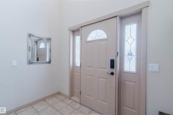 Entryway featuring a panel door with an arched window, sidelight with geometric textured glass, and tile flooring - 