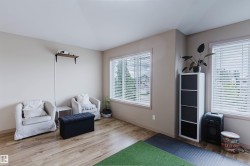 Bright room featuring light wood-finish flooring and two large windows with blinds - 
