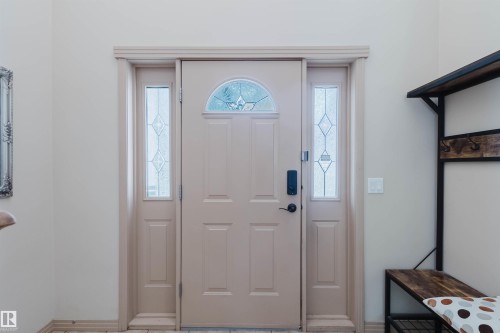 Entryway featuring a panel door with a decorative arched window, sidelight windows with leaded glass, and a black digital lockset - 2236 Garnett Crest, Edmonton, AB 