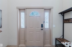 Entryway featuring a panel door with a decorative arched window, sidelight windows with leaded glass, and a black digital lockset - 