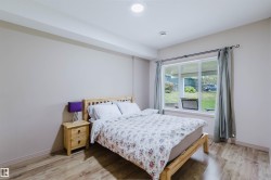 Bedroom featuring wood-finish flooring, a large window, a ceiling light fixture, and neutral wall tones - 