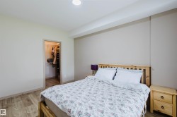 Spacious room featuring wood-finish flooring, a built-in closet with shelving and hanging rods, and neutral-toned walls - 