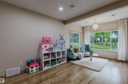 Spacious room featuring wood-finish flooring, a large picture window, recessed lighting, and a decorative chandelier - 