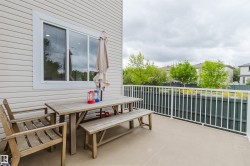Spacious outdoor balcony featuring a neutral-toned concrete surface, white picket railing, and a dark privacy fence - 