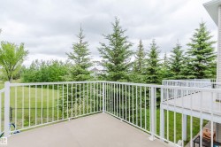 Private deck with white railing, overlooking a green lawn and mature evergreen trees - 