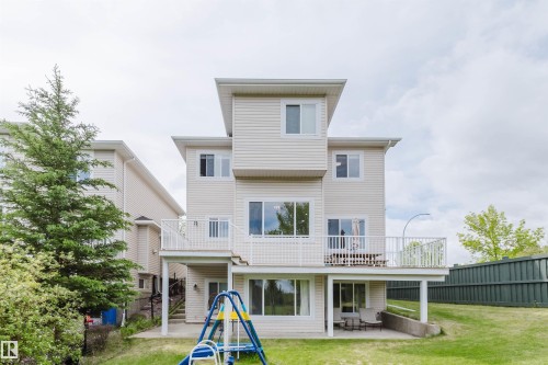 Private deck with white railing, overlooking a green lawn and mature evergreen trees - 2236 Garnett Crest, Edmonton, AB 