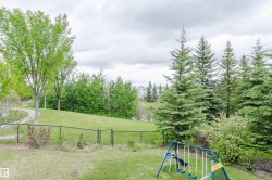 Expansive fenced backyard featuring a manicured lawn, mature trees, and a paved pathway - 