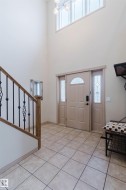 Two-story foyer with a decorative chandelier, transom window, and tiled flooring - 