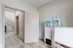 Interior room with wood-finish flooring, light neutral wall paint, and a white paneled door - 