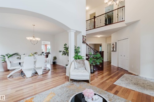 Open-concept living space featuring wood-finish flooring throughout, a two-story foyer, and a second-story balcony with dark wood railings - 20524 58 Avenue, Edmonton, AB 