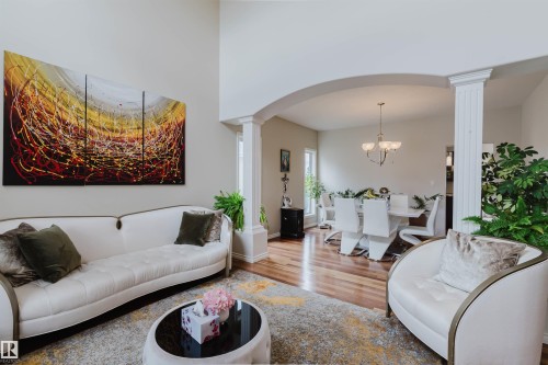 Vaulted ceilings frame the living space, featuring wood-finish flooring and an arched entryway - 20524 58 Avenue, Edmonton, AB 