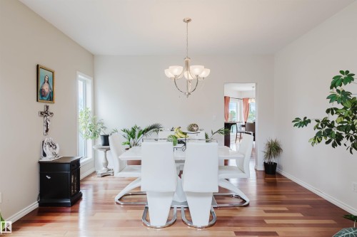 Dining area featuring wood-finish flooring, light-toned walls, and a five-light chandelier - 20524 58 Avenue, Edmonton, AB 