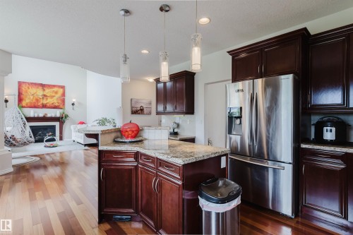 Kitchen with wood-finish flooring, dark wood cabinetry, and a stainless steel French door refrigerator - 20524 58 Avenue, Edmonton, AB 