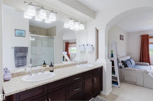 Bathroom featuring a double vanity with undermount sinks, a light-toned countertop, and dark wood-finish cabinetry - 20524 58 Avenue, Edmonton, AB 