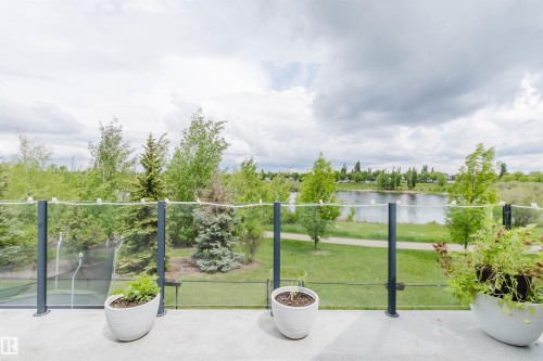 Concrete balcony with glass railing, overlooking a body of water, green spaces, and mature trees - 20524 58 Avenue, Edmonton, AB 
