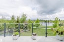 Concrete balcony with glass railing, overlooking a body of water, green spaces, and mature trees - 20524 58 Avenue, Edmonton, AB 