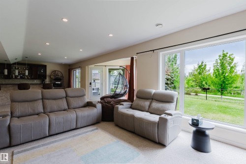 Bright lower-level living space featuring recessed lighting and a built-in wet bar with dark wood cabinetry and suspended lighting - 20524 58 Avenue, Edmonton, AB 