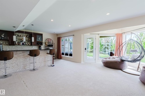 Spacious entertainment area featuring a built-in wet bar with dark wood cabinetry and pendant lighting - 20524 58 Avenue, Edmonton, AB 