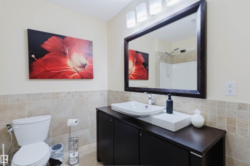 Bathroom featuring a dark wood-finish vanity with a vessel sink, a large framed mirror, and a three-light vanity fixture - 20524 58 Avenue, Edmonton, AB 