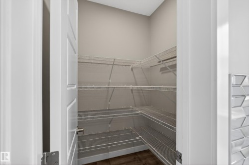 Spacious pantry featuring wire shelving, wood-finish flooring, and light neutral wall paint - 90 1010 Rabbitt Hill Road Sw, Edmonton, AB - Indoor With Storage