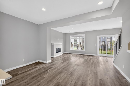 Open-concept living space with wood-finish flooring, recessed lighting, and a modern fireplace with white mantel - 90 1010 Rabbitt Hill Road Sw, Edmonton, AB - Indoor Photo Showing Living Room With Fireplace