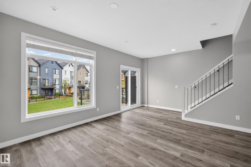 Spacious living area featuring wood-finish flooring, light gray walls, and recessed lighting - 90 1010 Rabbitt Hill Road Sw, Edmonton, AB - Indoor Photo Showing Other Room