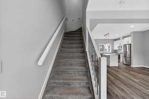 Carpeted staircase with white handrails and balusters, leading to an open-concept living space - 90 1010 Rabbitt Hill Road Sw, Edmonton, AB - Indoor Photo Showing Other Room