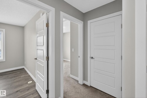 Interior hallway featuring light gray walls, white trim, and a combination of wood-finish flooring and carpet - 90 1010 Rabbitt Hill Road Sw, Edmonton, AB - Indoor Photo Showing Other Room