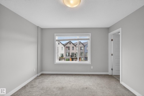 Bright room featuring light gray walls, plush gray carpeting, white trim, and a prominent window - 90 1010 Rabbitt Hill Road Sw, Edmonton, AB - Indoor Photo Showing Other Room