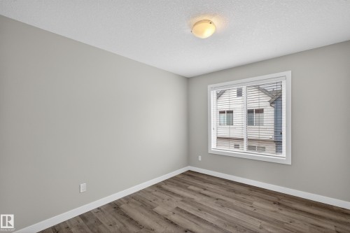 Neutral wall paint with wood-finish flooring, white baseboards, and a window featuring horizontal blinds - 90 1010 Rabbitt Hill Road Sw, Edmonton, AB - Indoor Photo Showing Other Room
