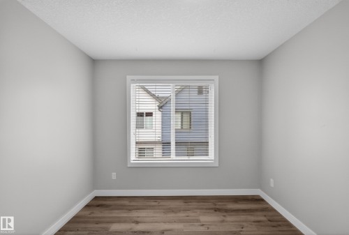 Interior room featuring wood-finish flooring, light gray wall paint, and white baseboards - 90 1010 Rabbitt Hill Road Sw, Edmonton, AB - Indoor Photo Showing Other Room