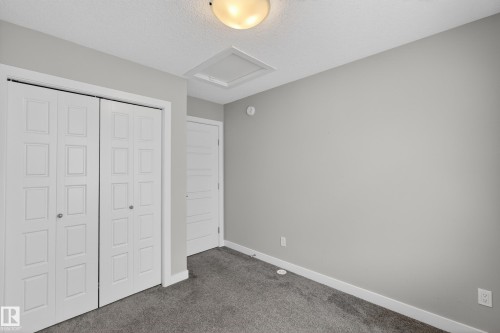 Neutral-toned room featuring a flush-mount ceiling light and a built-in closet with bi-fold paneled doors - 90 1010 Rabbitt Hill Road Sw, Edmonton, AB - Indoor Photo Showing Other Room