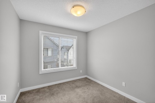 Neutral-toned interior room featuring light gray walls, white trim, and textured carpet flooring - 90 1010 Rabbitt Hill Road Sw, Edmonton, AB - Indoor Photo Showing Other Room