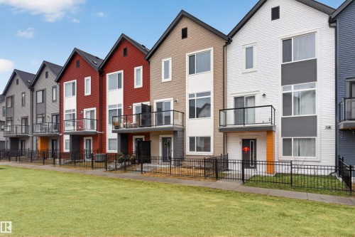Contemporary townhome with multiple balconies, a fenced yard, and a varied facade featuring board and batten siding - 90 1010 Rabbitt Hill Road Sw, Edmonton, AB - Outdoor With Balcony With Facade