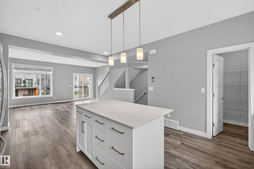 Kitchen island featuring white cabinetry, a light-toned countertop, and modern pendant lighting - 90 1010 Rabbitt Hill Road Sw, Edmonton, AB - Indoor