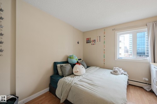 Bright room featuring a large window with white trim, wood-finish flooring, and neutral wall paint - 901 9710 105 Street, Edmonton, AB - Indoor Photo Showing Bedroom