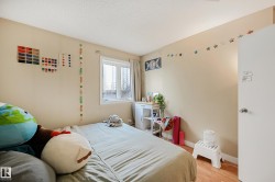 Bedroom with light-toned walls, wood-finish flooring, a double window, and a white interior door - 