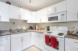 Well-appointed kitchen featuring abundant white cabinetry with brushed nickel hardware, laminate countertops, a double basin stainless steel sink, a white electric range, and a white over-the-range microwave - 