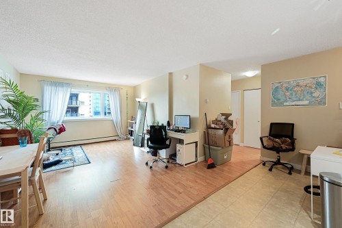 Open-concept living area featuring wood-finish flooring transitioning to neutral-toned tile - 901 9710 105 Street, Edmonton, AB - Indoor