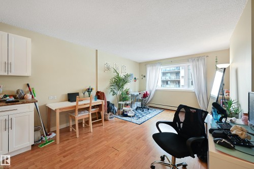 Bright living area featuring wood-finish flooring, a large window, and light-toned walls - 901 9710 105 Street, Edmonton, AB - Indoor