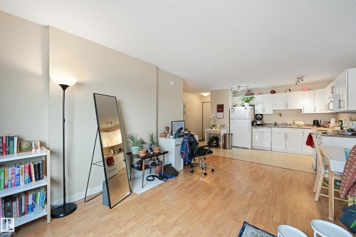 Open-concept living space featuring wood-finish flooring, white kitchen cabinetry, white appliances, and track lighting - 901 9710 105 Street, Edmonton, AB - Indoor