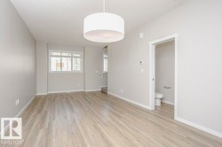 Spacious living area featuring light-toned flooring, neutral wall paint, and a modern drum pendant light fixture - 