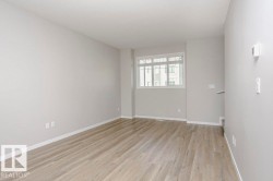 This interior space features light-toned walls, wood-look flooring, and a window with blinds providing natural light - 