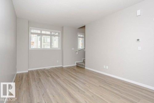 This spacious room features durable plank flooring, light-colored walls, and a window that provides natural light - 320 Secord Boulevard, Edmonton, AB - Indoor Photo Showing Other Room