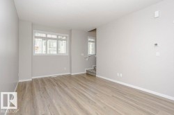 This spacious room features durable plank flooring, light-colored walls, and a window that provides natural light - 