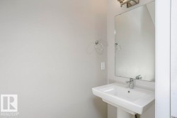 Bathroom featuring a pedestal sink with a chrome faucet, a rectangular mirror, and a wall-mounted light fixture - 