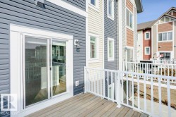 The property features a private deck with white railings, a sliding glass door for access, and exterior siding in a combination of blue and white tones - 