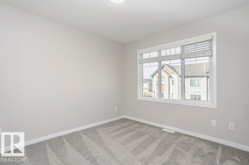 This room features light grey walls, a window with blinds, and grey patterned carpeting - 320 Secord Boulevard, Edmonton, AB - Indoor Photo Showing Other Room