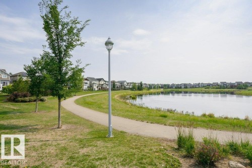 This property features a paved pathway alongside a tranquil body of water, offering scenic views of surrounding homes - 320 Secord Boulevard, Edmonton, AB - Outdoor With Body Of Water With View