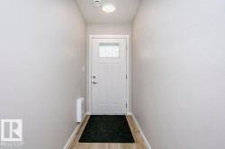 Entryway featuring light-colored walls, wood-look flooring, and a white front door with an integrated window - 